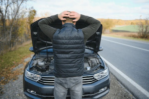 confused man looking at his broken down car